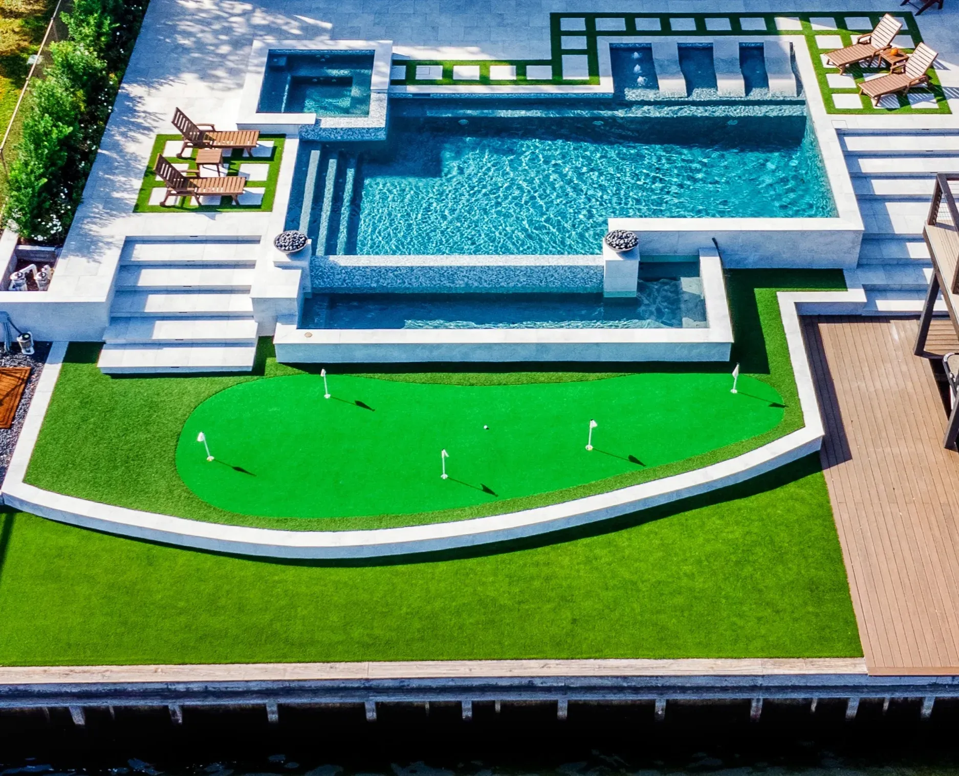 The stepped pool and curved practice green from above, with the seawall and water below