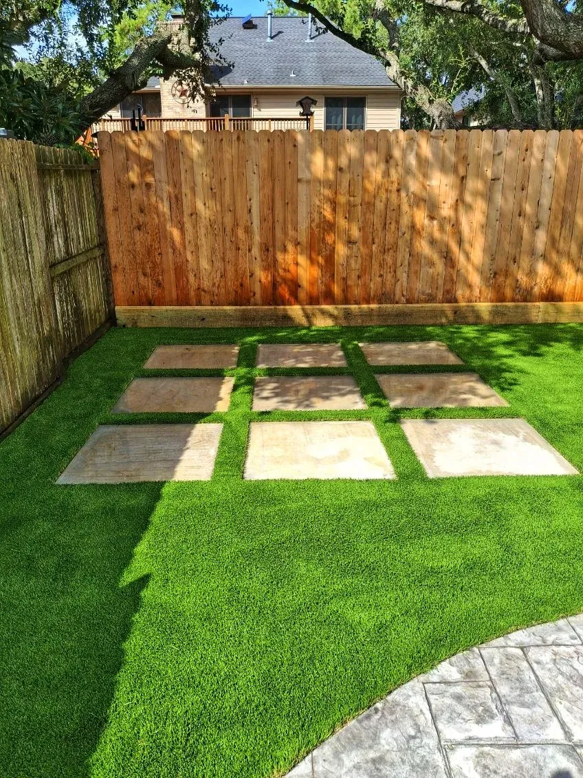 A backyard turf lawn with square stepping stones laid in a grid pattern
