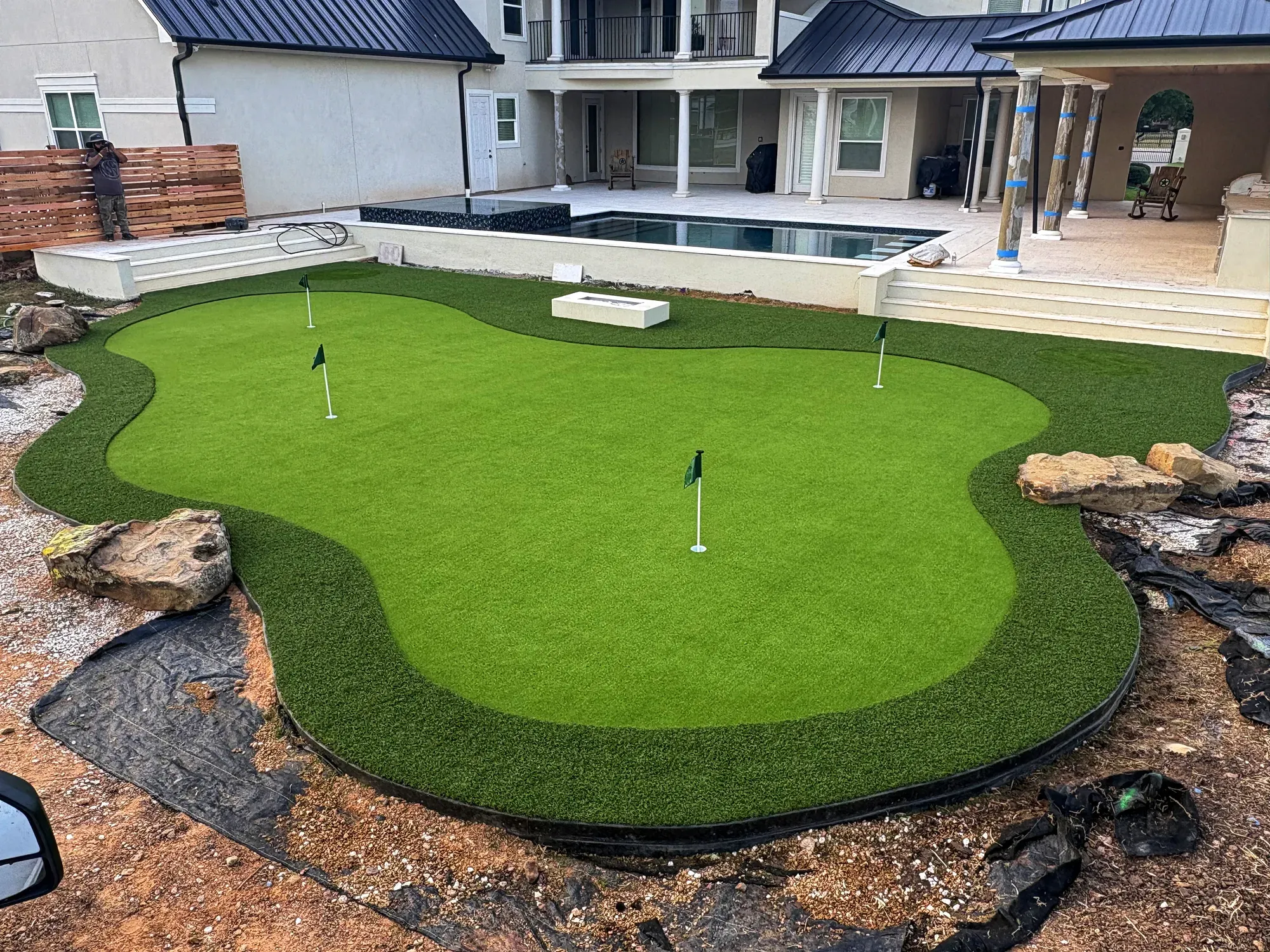 A free-form practice green with boulders and gravel edging