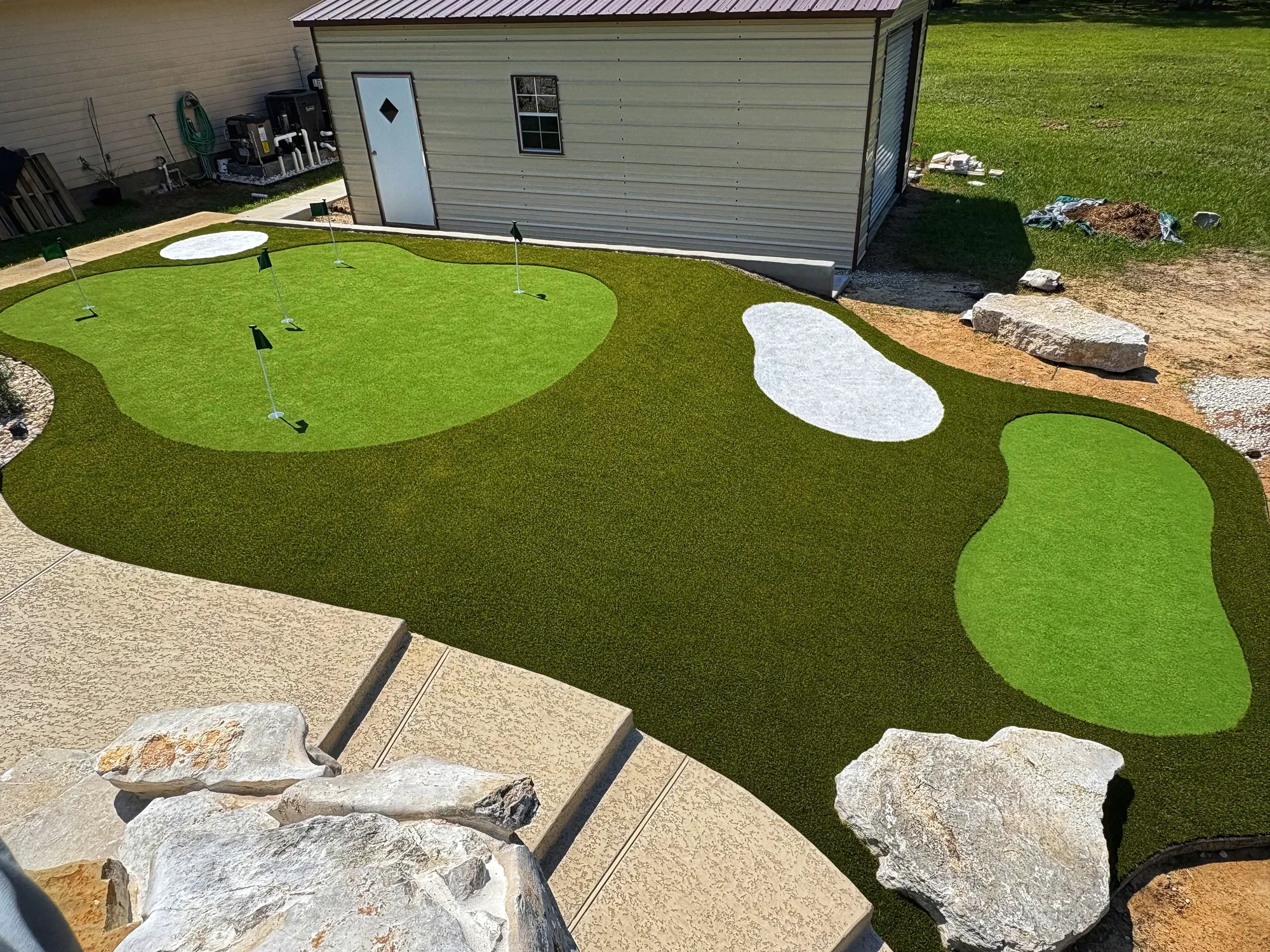 The shaped practice green with its bunker, decomposed granite and a boulder border