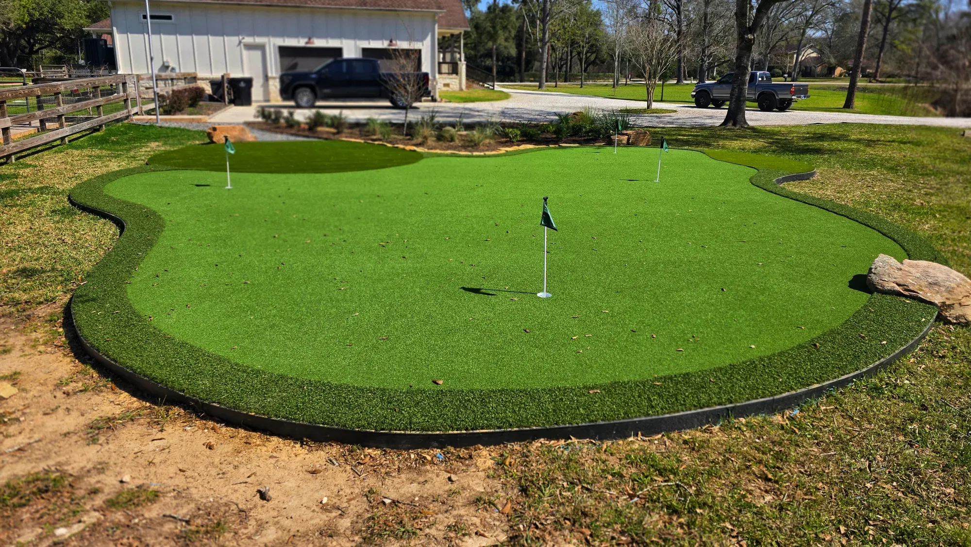 A free-form practice green with flags, edged by boulders and gravel