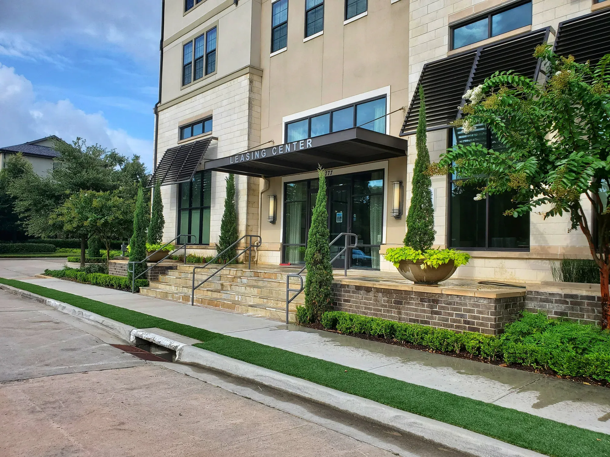 Strip of artificial turf running along the sidewalk in front of a leasing centre entrance