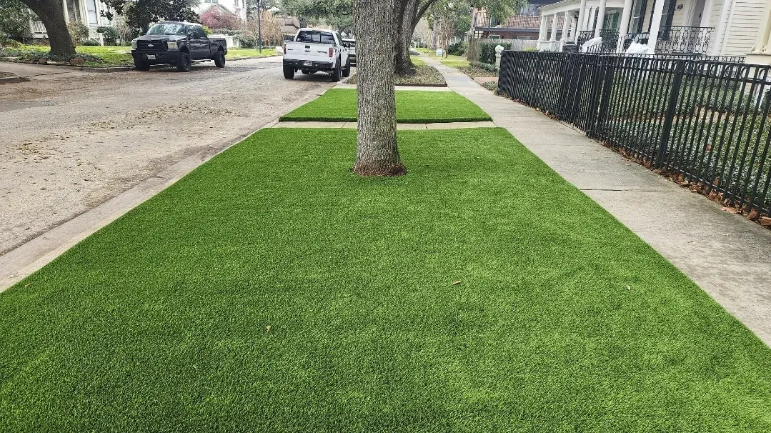 An artificial turf verge around a street tree between sidewalk and roadway