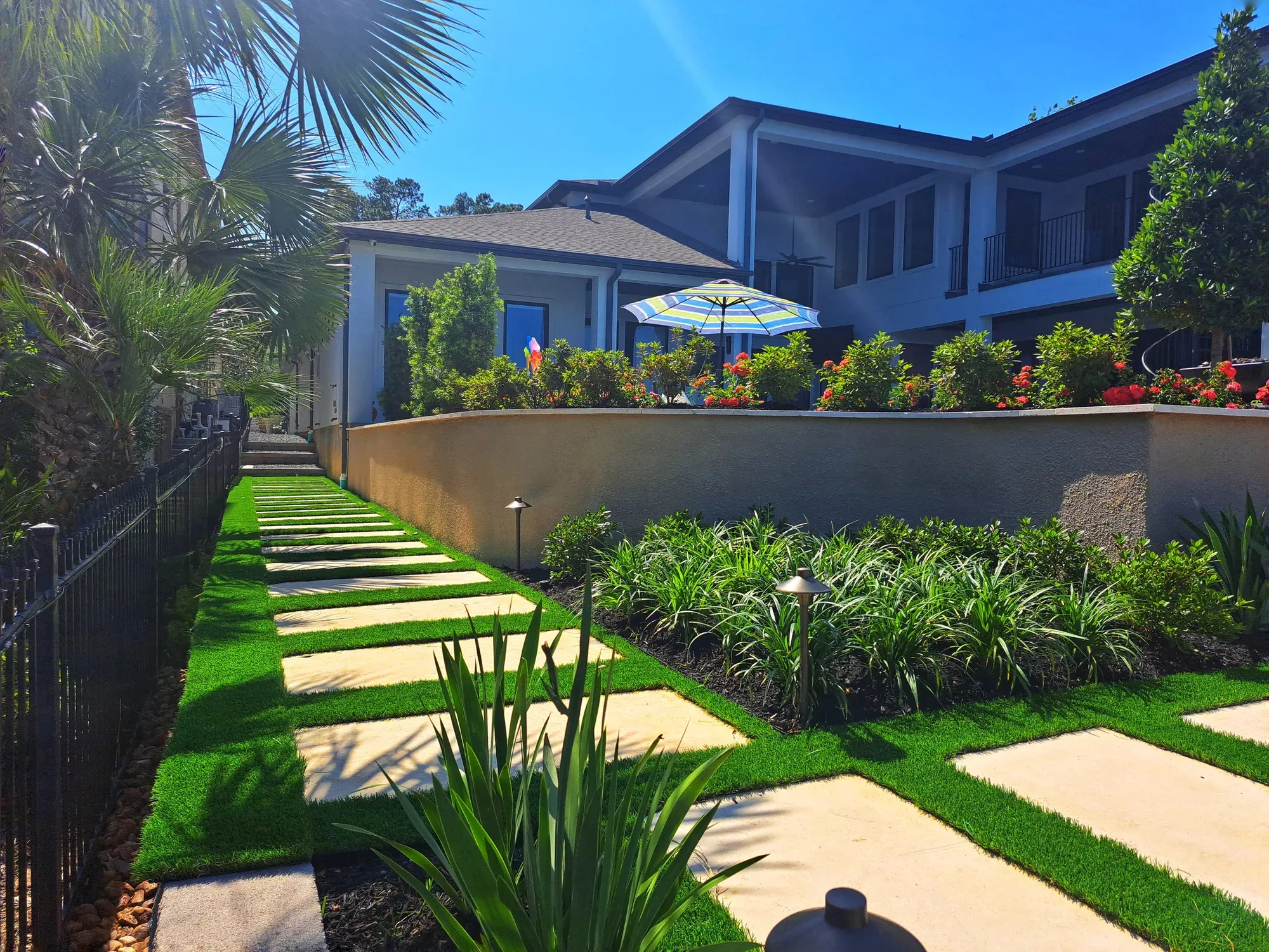 A garden path of pale stone treads with turf joints, running beside a raised terrace and planting