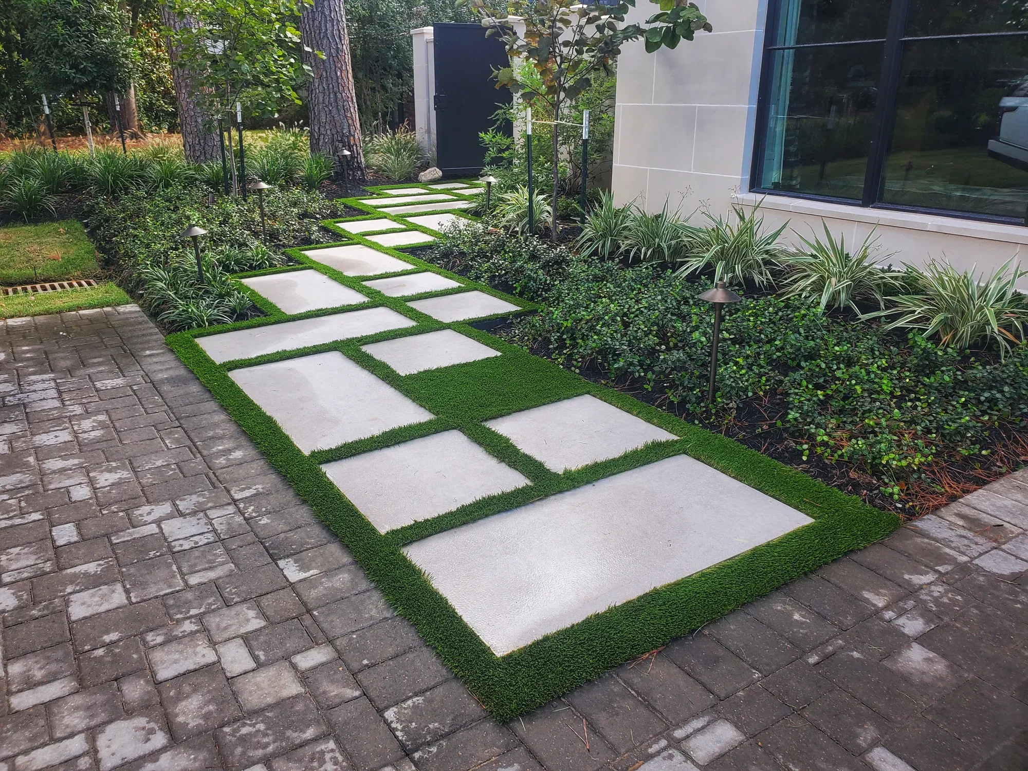 Stone treads with turf joints leading past a planted bed and a glazed wall