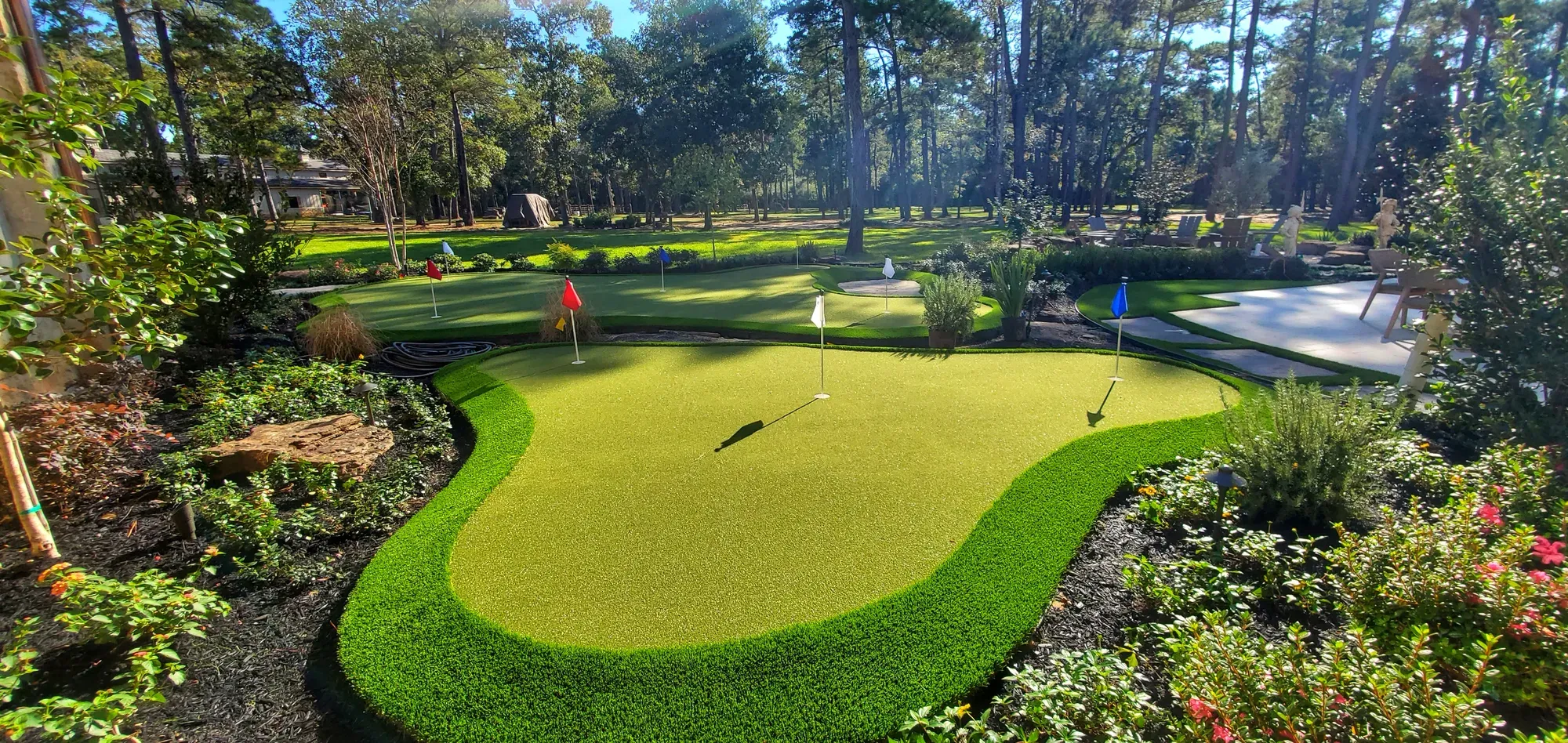 A multi-hole practice green with coloured flags, set among planted beds