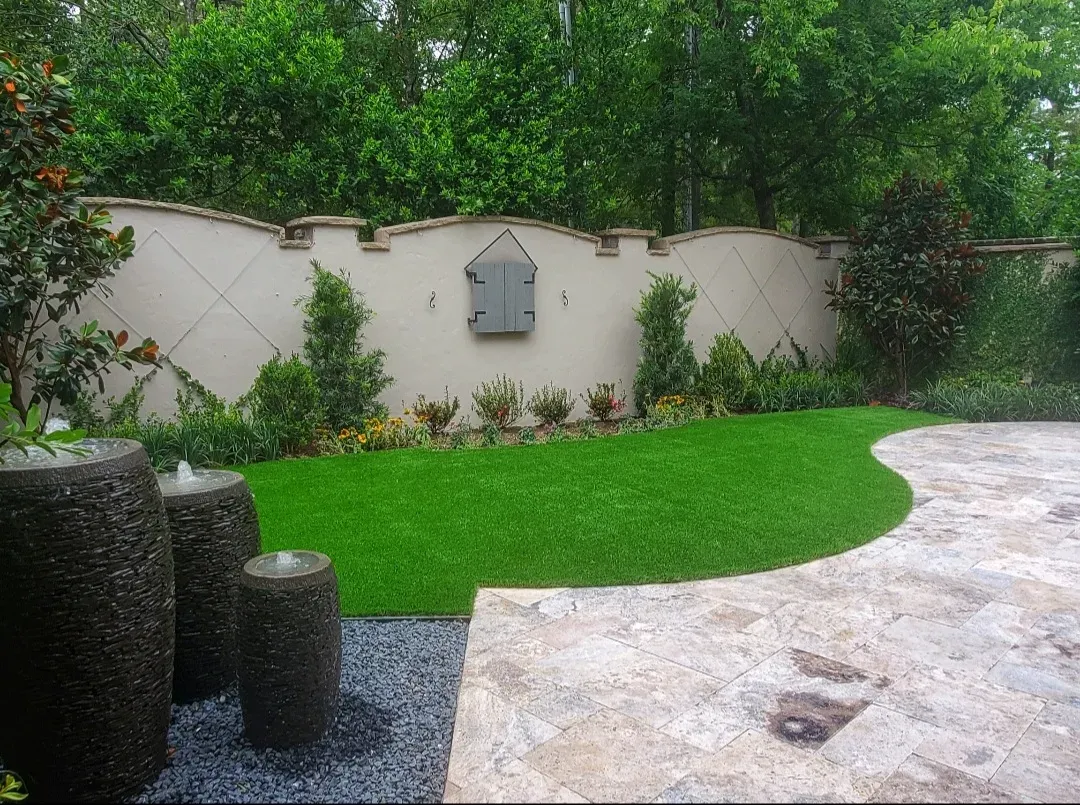 A curved artificial lawn beside a stone terrace with dark water-feature bowls