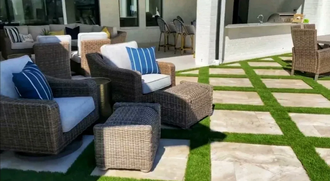 Wicker lounge chairs on a covered terrace of paving with turf strips running through it