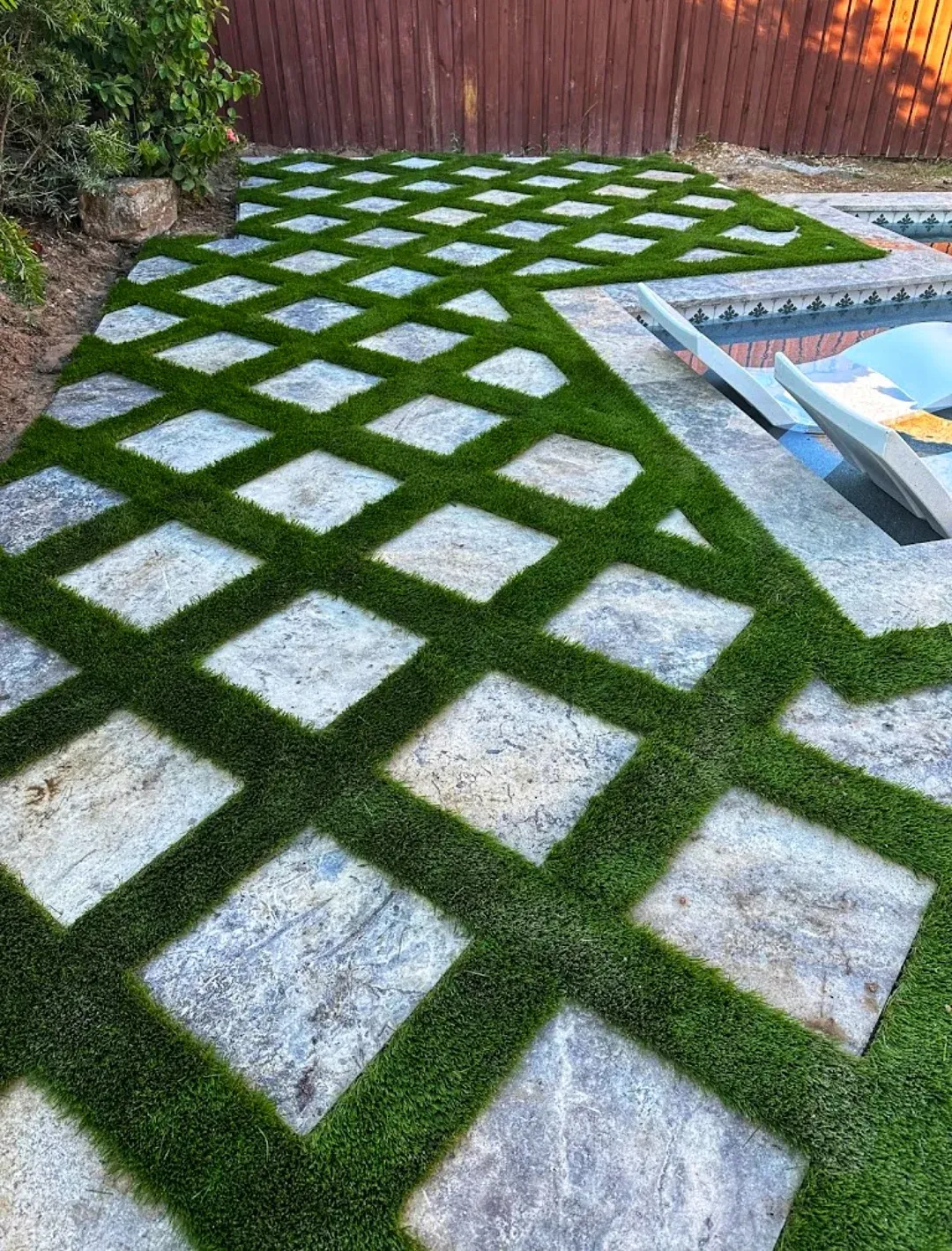 A diamond grid of pavers and turf joints running to the pool