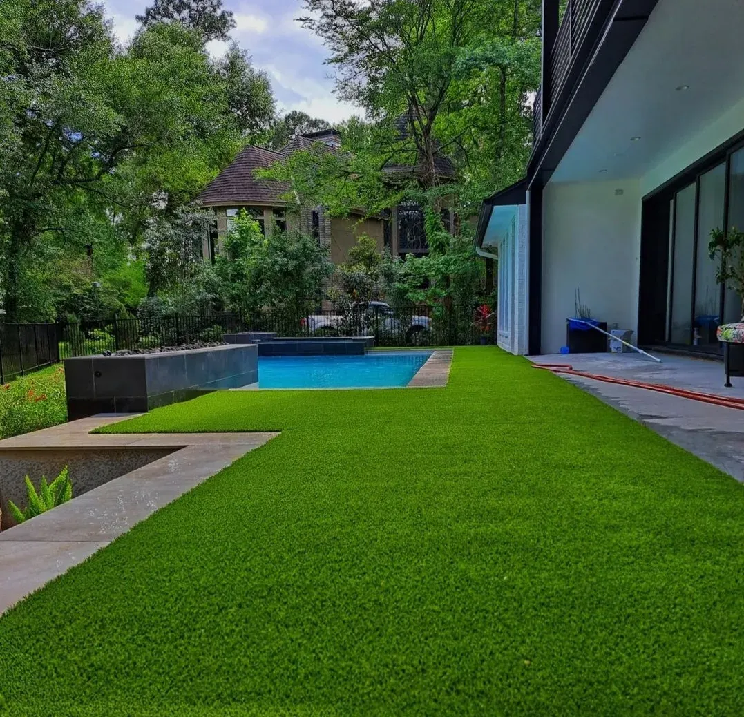An artificial lawn beside a linear pool at a modern house set among pines