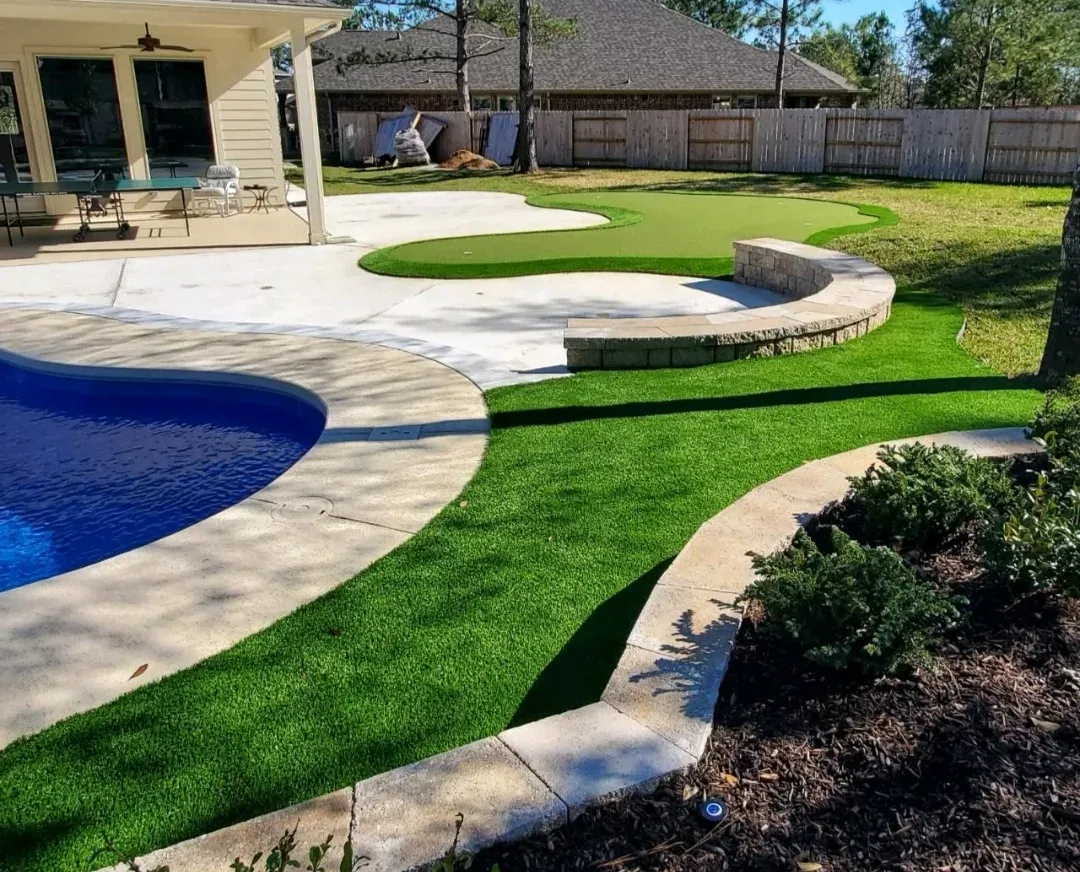 A curved pool with a practice green and turf lawn wrapping its deck