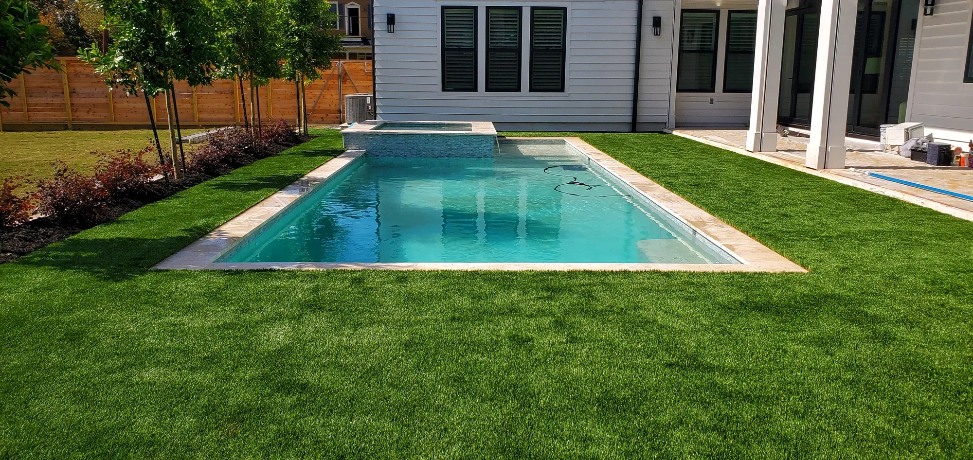 A rectangular pool with artificial turf running to the fence line