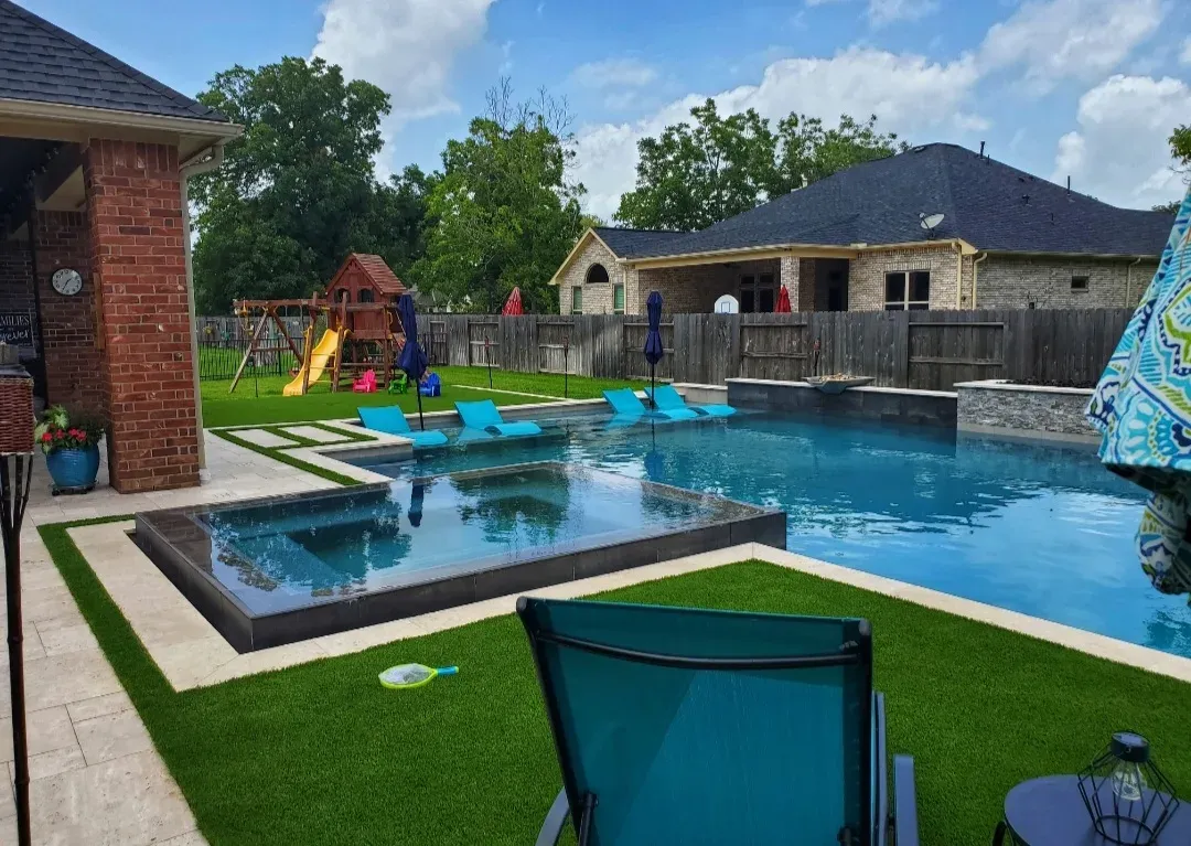The pool and spa from the covered patio, turf running around the deck