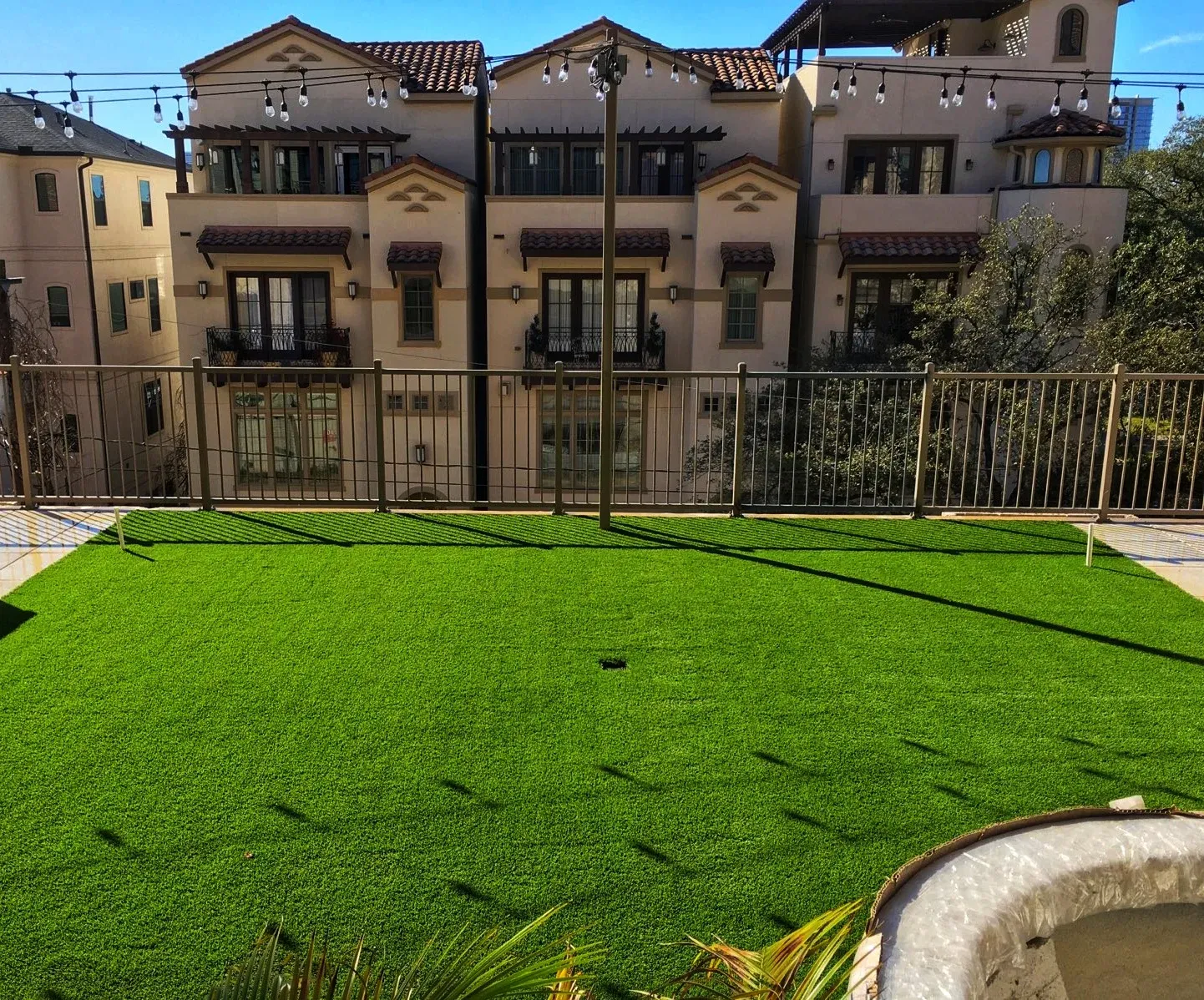 A rooftop turf terrace above the street, with apartment buildings beyond