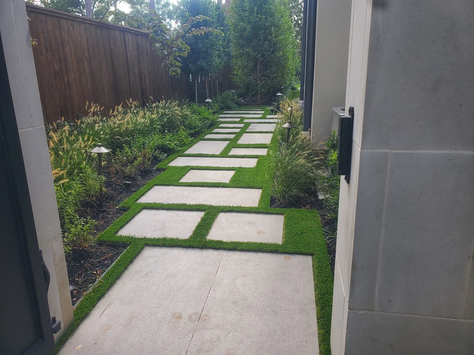 Large stone treads with turf joints running between a rendered wall and a planted border