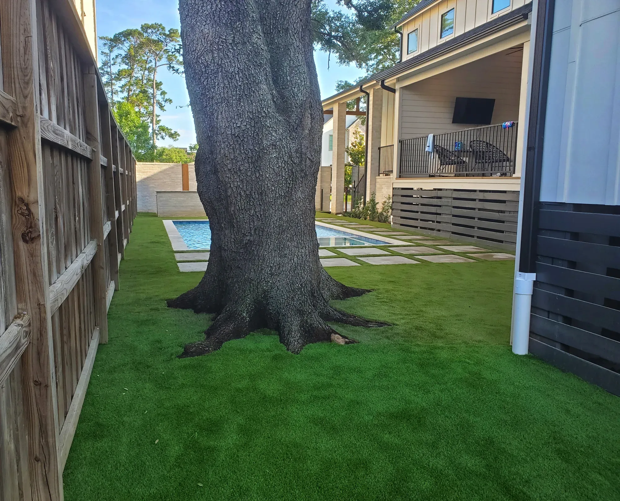 Artificial turf laid around the trunk of a large mature tree in a side yard