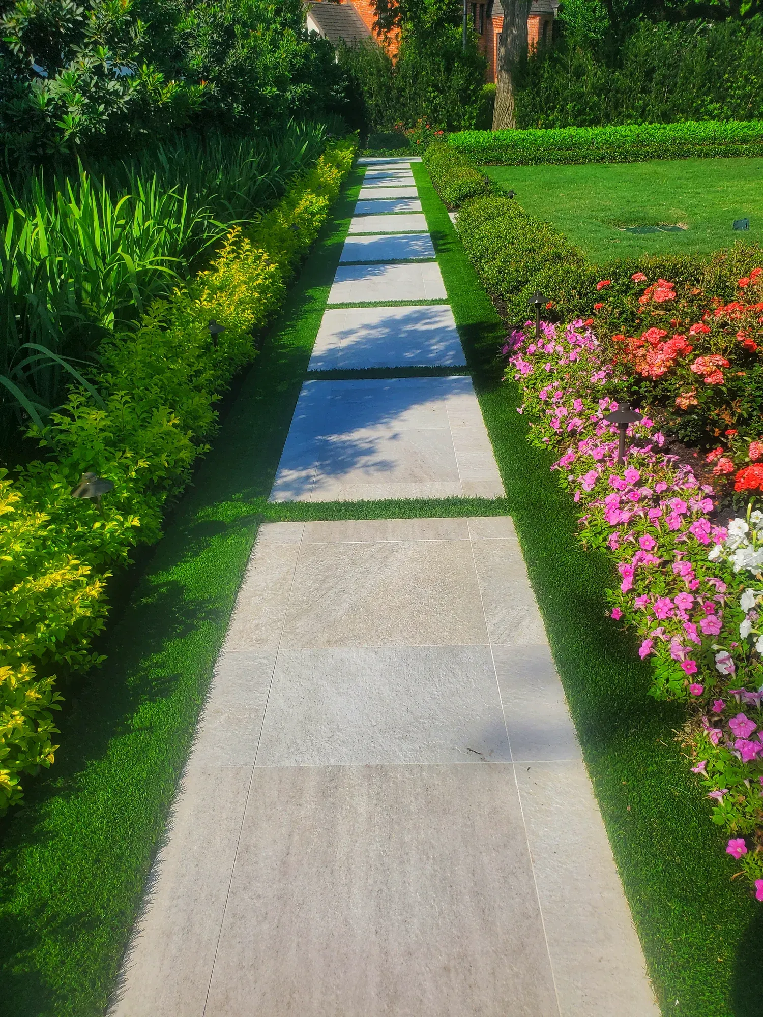 A stone walk with turf joints running between deep flowering borders