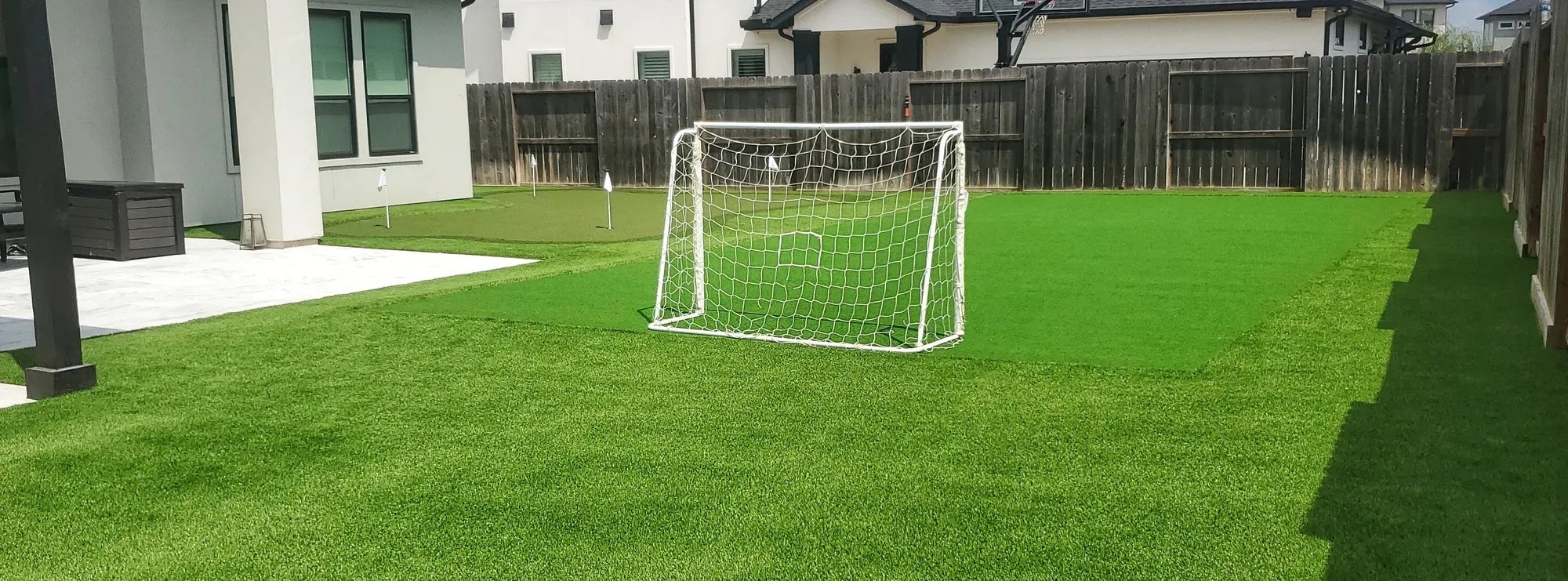 One artificial turf field carrying a full-size soccer goal at one end and a flagged putting green at the other