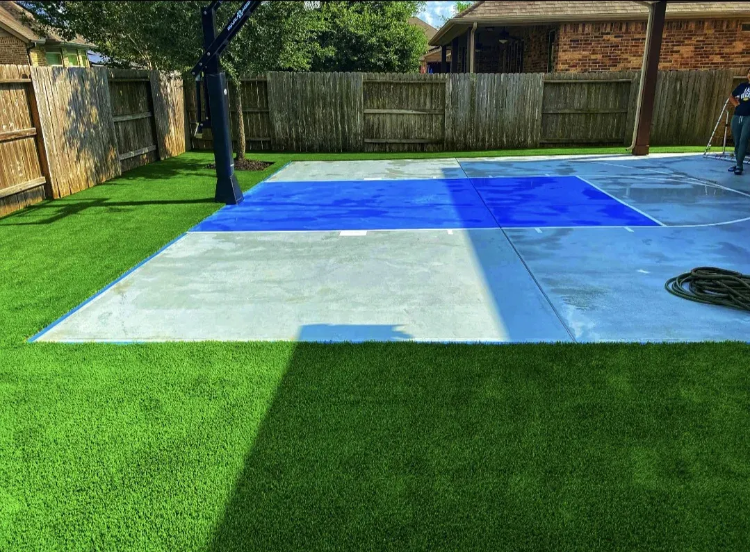 A blue-painted sport court with artificial turf laid around it